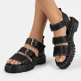 Sandalia de estilo chunky color negro, con suela track dentada y tres tiras ajustables con hebillas metálicas.