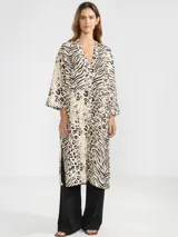 Camisa larga de lino 100% italiano, con estampado animal print que combina motivos de cebra y leopardo. Presenta un corte de estilo japonés, escote en V con tres botones delanteros y mangas tres cuartos anchas.