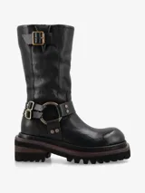Bota de cuero negro de inspiración biker con caña media. Presenta un diseño robusto con correas ajustables, hebillas metálicas y una argolla decorativa con tachas en el tobillo. Posee suela track de goma para mayor tracción y estabilidad.