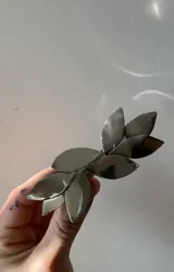 Aplique para el pelo color plateado con forma de rama con hojas.