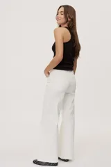 Pantalón de tiro medio y corte wide leg color beige, con diseño clásico de cinco bolsillos, presillas para cinto y cierre frontal con botón y cremallera.