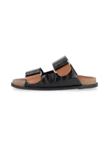 Sandalias de dos tiras anchas en cuero negro con textura de cocodrilo, detalle de remaches metálicos y base de corcho con plantilla marrón.