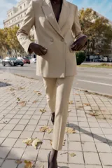 Blazer cruzado de cuello solapa y manga larga, en color beige, con bolsillos con solapa en el delantero y cierre frontal con botones forrados.