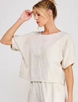 Blusa corta de lino y viscosa color beige, con bordado de grandes flores al tono, cuello redondo, mangas cortas abullonadas y corte holgado.