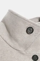 Abrigo corto de paño con cuello clásico, manga larga y cierre frontal cruzado con botones. Incluye bolsillos delanteros de vivo y cinturón ajustable del mismo tejido.