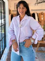 Camisa de manga larga con diseño de rayas verticales en tonos celeste y blanco. Presenta cuello clásico, cierre frontal con botones y mangas con puños acampanados con volados.