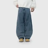 Pantalón de jean estilo baggy, de corte extremadamente holgado y tiro medio. Presenta bolsillos traseros con bordes deshilachados y un diseño de llamas bordado en uno de ellos. El ruedo cuenta con un acabado reforzado y ancho.