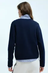Saco entallado de punto fino, color azul marino, con cuello redondo, cierre frontal de botones y detalle de corazón bordado en el frente.
