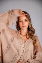 Camisa negra de manga larga con detalles de encaje en hombros y puños. Presenta un cuello tipo solapa y cierre frontal con botones dorados.