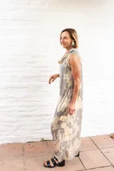 Vestido largo de corte recto y holgado, con cuello tipo polera drapeado y sin mangas. Presenta un estampado abstracto en tonos grisáceos y beige.