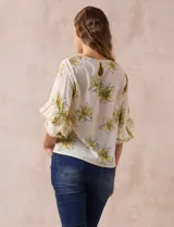 Blusa de gasa estampada con flores azules y violetas sobre fondo blanco, de manga 3/4 con volados.