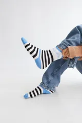 Medias de algodón con diseño a rayas verticales negras y blancas, con detalles en azul celeste en el talón, puntera y puño. Presentan texto bordado en la caña.