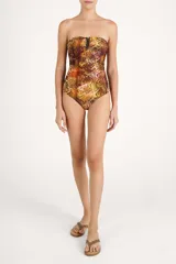 Malla enteriza strapless con estampado de serpiente en tonos marrones y dorados, con detalle de abertura en el escote bordeada con cuentas oscuras y fruncidos laterales.