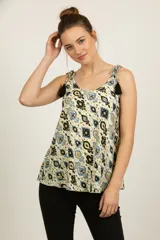 Musculosa de poliéster con estampado ikat en tonos crema, azul claro, negro y dorado. Presenta escote redondo y breteles finos anudados con borlas negras decorativas.