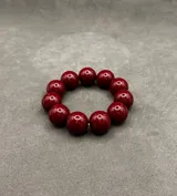 Pulsera elástica compuesta por cuentas esféricas de resina en tonos verde lima, naranja y bordó.