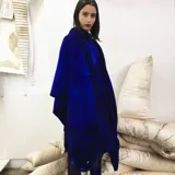Capa azul de lana merino afieltrada, con guarda tejida en cuello y ruedo. Se puede usar como poncho o como capa abierta.