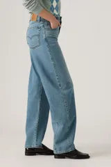 Pantalón de jean de corte baggy con diseño barrel, tiro medio y lavado azul claro con efecto desgastado. Presenta costuras laterales curvadas que definen su silueta amplia y relajada.