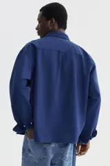 Camisa de manga larga H&M de corte relajado, confeccionada en algodón Oxford azul marino. Cuenta con cuello americano, bolsillo aplicado en el pecho y botones frontales blancos.