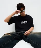 Remera de corte oversized en color negro, con cuello redondo y manga corta. Presenta un estampado frontal con la palabra 'Brutal' en tipografía estilo metal y un estampado de esqueleto en la espalda.