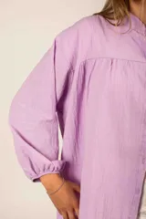 Camisa de lino liviano color beige, con cuello clásico, cierre frontal de botones, hombros caídos y mangas con terminaciones elásticas.