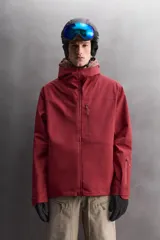 Cazadora deportiva de esquí con diseño bicolor en tonos negro y verde oliva. Presenta capucha amplia con visera, cierre frontal con cremallera termosellada, bolsillos frontales y en manga con cierres impermeables, y aberturas de ventilación en las axilas. Incluye faldón interior antinieve, puños ajustables y tecnología de rescate RECCO.