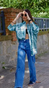 Chaqueta celeste con lentejuelas, corte tipo camisa, de manga larga y con bolsillos frontales.