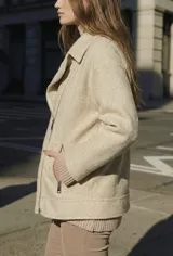 Campera de textura bouclé en color tostado, con diseño de solapas amplias, cierre frontal cruzado y mangas largas. Presenta un corte estructurado y moderno.