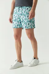 Short de baño con estampado botánico en tonos turquesa, blanco y azul. Presenta cintura elástica con cordón ajustable, dos bolsillos laterales y uno trasero, además de un logo bordado en la pierna.