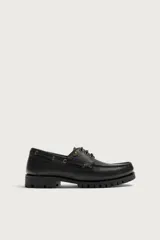 Zapato estilo náutico de piel color negro, de la colección especial Fruit of the Loom x Zara. Presenta detalle de bordón en el empeine, ojalillos metálicos dorados, cordones negros y suela track dentada.
