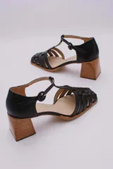 Guillerminas clásicas de cuero negro con diseño de tiras entretejidas, pulsera con hebilla y taco de madera.