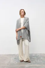 Ruana de tejido de punto grueso en color gris, con diseño de cuello alto y terminaciones acanaladas en los bordes.