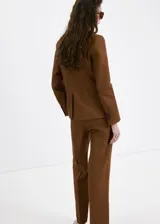 Blazer de lino color marrón, de diseño recto, con cuello pico con solapa, manga larga y cierre de un botón en la parte delantera.