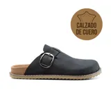 Zueco de cuero gamuzado color beige, con diseño de punta cerrada, hebilla metálica lateral y suela de corcho con base dentada.