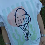 Remera blanca de algodón con estampa frontal ilustrada en tonos celestes y rosados, de corte holgado y mangas cortas.