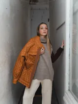 Campera acolchada color ladrillo con cuello marrón de pana, cierre frontal con botones a presión y bolsillos laterales.