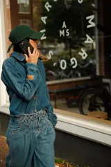 Camisa de jean estilo oversize con cuello camisero, cierre frontal con botones y mangas largas con puños. Presenta un diseño de denim clásico con costuras visibles.