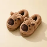 Pantuflas cerradas de peluche color beige con diseño de capibara, incluyendo orejas y nariz bordada. Cuentan con suela antideslizante.