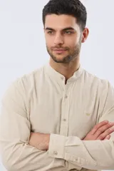 Camisa de lino y algodón color beige, de manga larga con cuello mao y cierre frontal de botones. Presenta un pequeño logo bordado en el pecho.