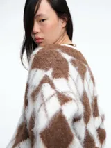 Sweater de tejido de punto con diseño de rombos en tonos marrón y blanco, escote en V y mangas largas.