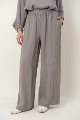 Pantalón palazzo de lino color gris, de corte ancho, con cintura elástica, bolsillos laterales y detalle de alforzas verticales a los costados.