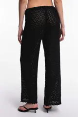 Pantalón blanco de tejido calado con diseño de rombos, cintura elástica con cordón ajustable y ruedo con terminación ondulada.