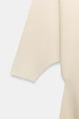 Vestido midi de punto color marfil con escote en V, mangas largas de sisa ancha, cintura entallada y falda de corte evasé.