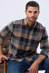 Camisa de viyela a cuadros en tonos marrón, azul marino y gris, con cuello clásico, cierre frontal con botones, mangas largas y un bolsillo en el pecho.