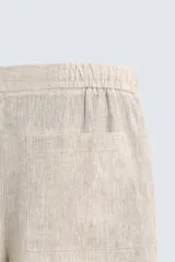 Bermuda de lino color blanco hueso, de corte relajado y tiro medio. Presenta cintura elástica ajustable con cordón, pliegues frontales y bolsillos laterales y trasero.