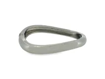 Brazalete rígido de metal plateado con diseño escultural, asimétrico y acabado pulido, con cierre de bisagra integrado.