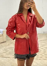 Blazer largo de cuero sintético color rojo vibrante, con cuello solapa, manga tres cuartos y un solo botón de madera en el frente.