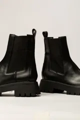 Bota Chelsea color verde militar de cuero, con elásticos laterales negros, tirador trasero y suela track negra.