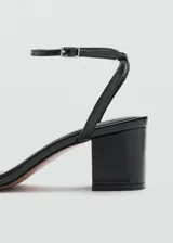 Sandalia de tacón bloque color negro, con diseño de tira delantera y cierre de pulsera al tobillo con hebilla metálica.