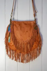 Cartera bandolera de cuero color terracota con pátina marrón, adornada con flecos y correa ajustable.