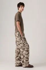 Pantalón cargo de corte amplio con estampado de camuflaje en tonos beige, marrón y verde. Cuenta con cintura elástica ajustable con cordón, bolsillos laterales con solapa y bolsillos traseros.